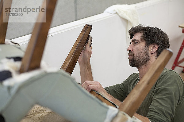 Ein konzentrierter Handwerker poliert das Bein eines antiken Stuhls