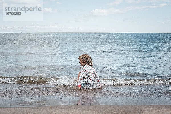 Mädchen spielt im Wasser am Strand und hat Spaß