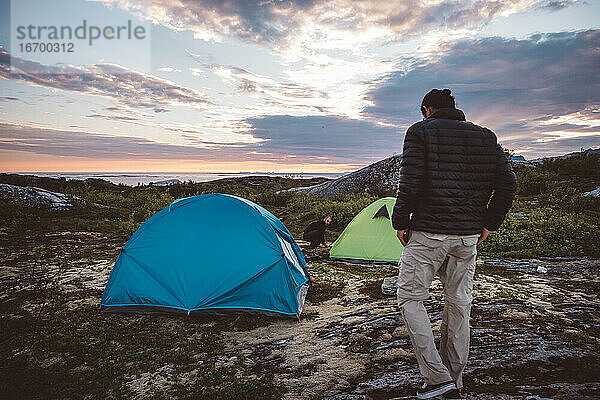 2 Männer auf einem Campingplatz bei Sonnenuntergang und bewölktem Himmel