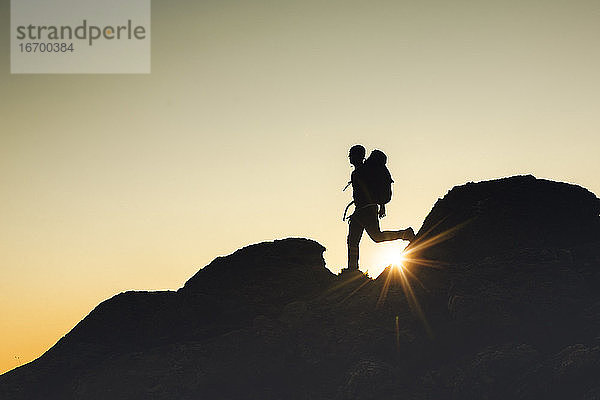 Mann Silhouette über einen Felsen bei Sonnenuntergang