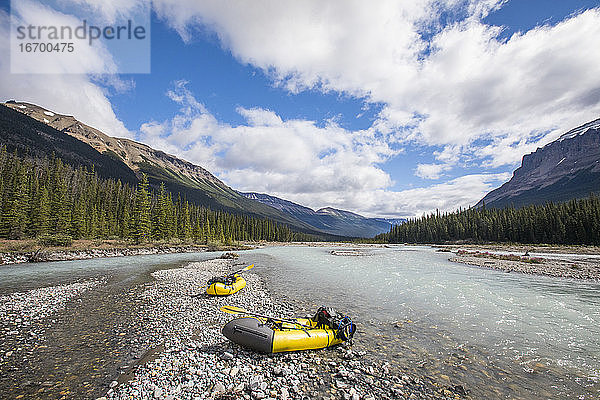 Landschaftlicher Blick auf zwei Packwagen am Flussufer im Banff National Park.