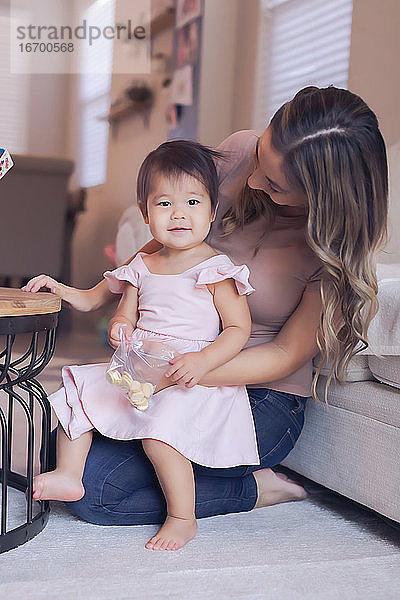 Die kleine Tochter isst mit ihrer Mutter im Wohnzimmer
