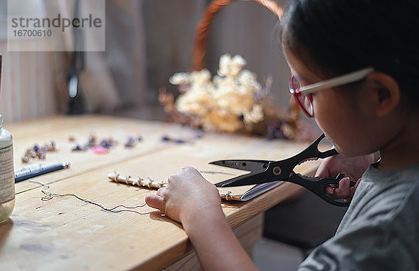 Ein Mädchen schneidet ein Seil auf ihrer Hand Handwerk Arbeit