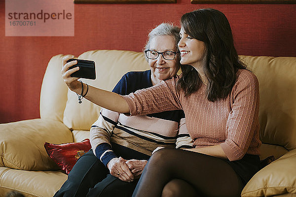 Enkelin und Großmutter machen ein Selfie auf dem Sofa