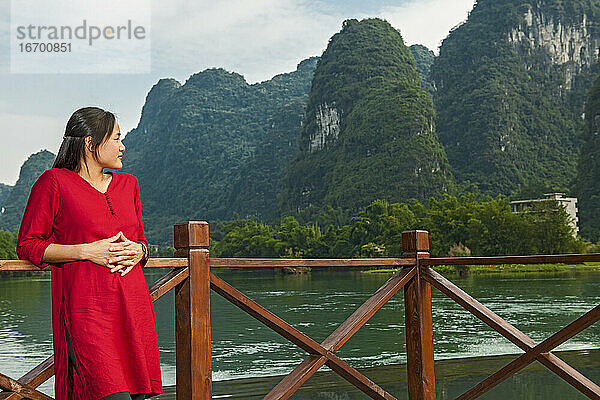 schöne Frau  die ihre Ellbogen auf die Brüstung neben dem Fluss Li stützt