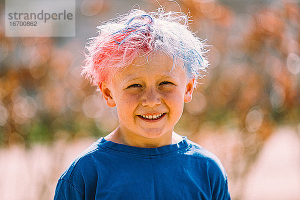 Porträt eines Jungen mit gefärbtem Haar  der in die Kamera lächelt