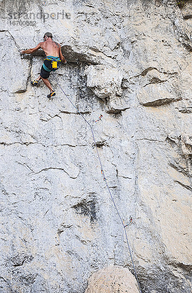Mann klettert an einer Felswand in Yangshuo