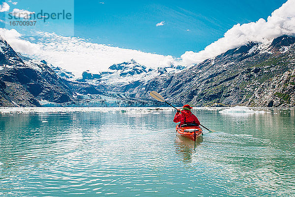 Frau beim Kajakfahren im Glacier Bay National Park mit Gletscher im Hintergrund