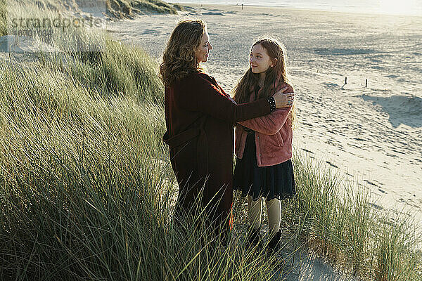 Mutter und Tochter am Strand stehend mit Blick aufs Meer