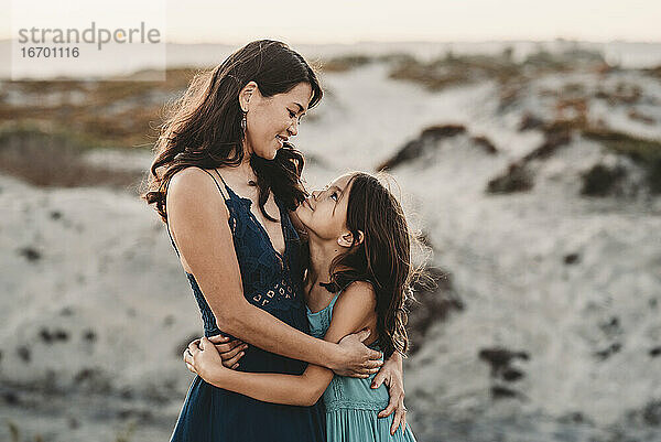 Glückliche Mutter  die ihre 8 Jahre alte Tochter am Strand umarmt