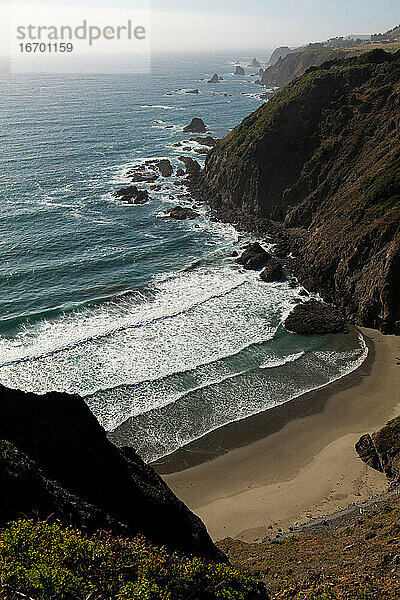 Abgeschiedene Bucht mit Meereswellen und goldenem Sand in Kalifornien
