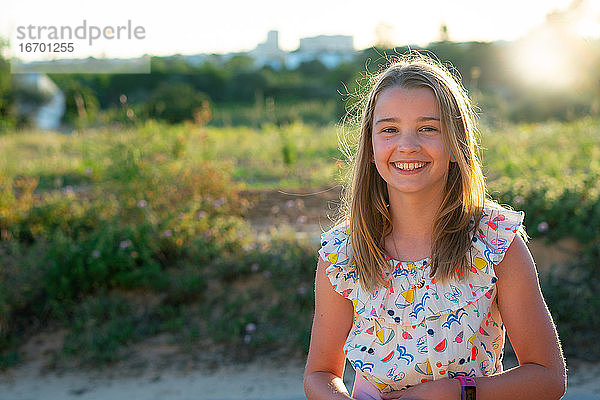 Lächelndes Mädchen im Sommerkleid mit Hintergrundbeleuchtung
