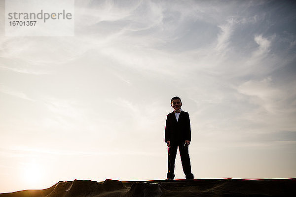 Neunjähriger Junge in Silhouette auf einem Felsen am Strand von San Diego stehend