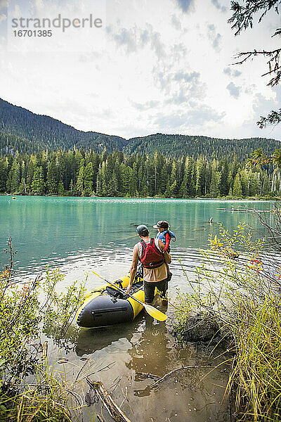 Vater hebt Sohn in Schlauchboot in einem Bergsee im Freien Einstellung