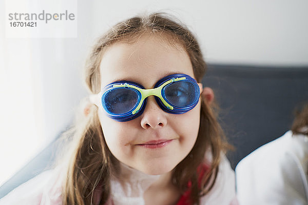 Glückliches Mädchen mit Schwimmbrille auf dem Sofa liegend