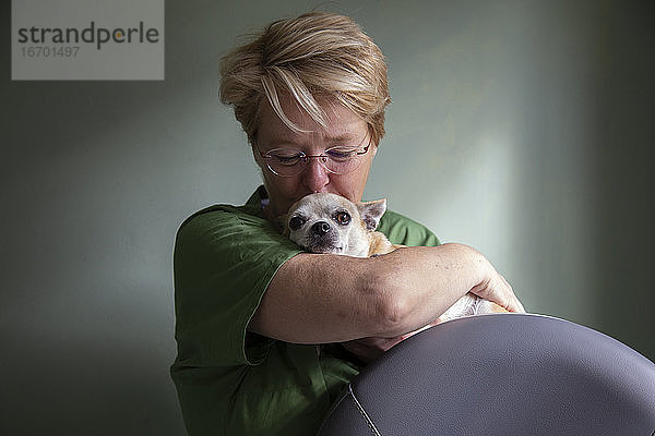 Eine Ärztin küsst ihren Chihuahua auf den Kopf