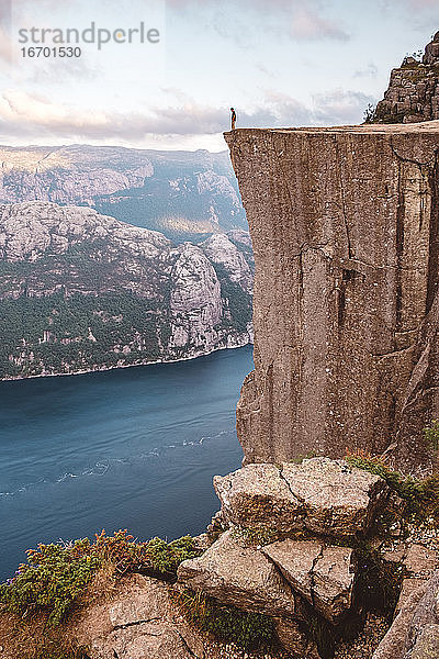 Mann steht und blickt auf den Rand einer Klippe am Preikestolen  Norwegen