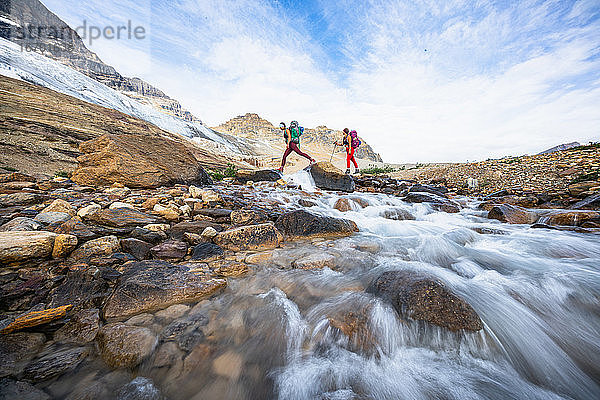 Weibliche Rucksacktouristen beim Überqueren eines Flusses während einer Wanderung auf dem wunderschönen Iceline Trail