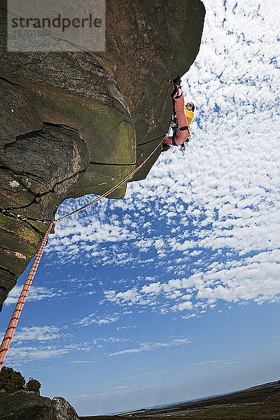 Frau beim Klettern an den Windgather-Felsen im britischen Peak District