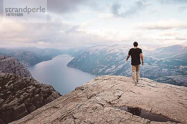 Mann geht am Rande einer Klippe am Preikestolen  Norwegen