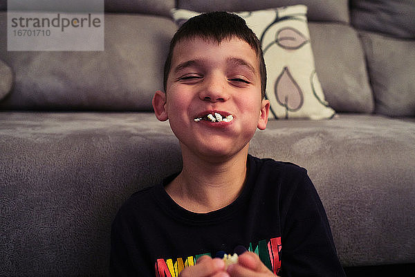 ein Kind  das Popcorn isst und dabei lacht  weil es ihm aus dem Mund kommt