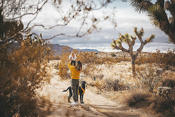 Eine Frau mit einem Baby und einem Hund steht in der Wüste von Kalifornien