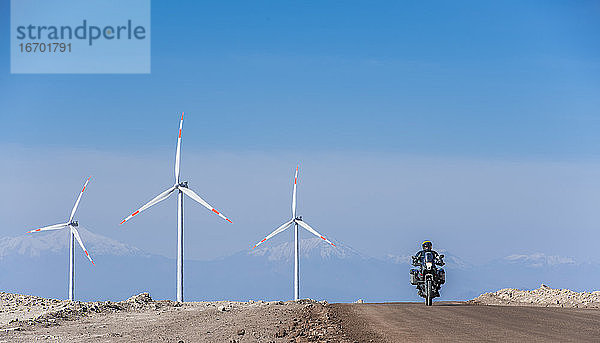 Mann auf seinem ADV-Motorrad in einem Windpark in der abgelegenen Atacama-Wüste