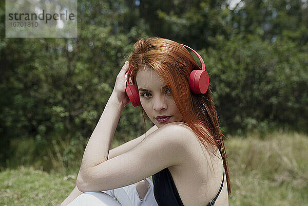 süßes rothaariges Mädchen hört Musik im Park