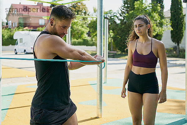 Junger Mann und Frau machen Gymnastik mit einem Gummiband
