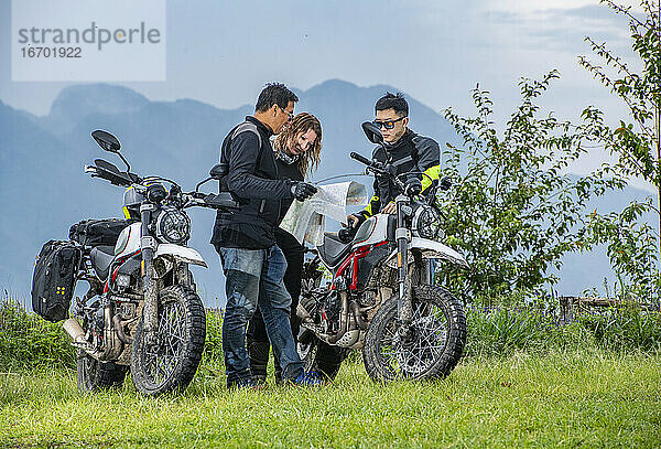 Drei Freunde schauen auf einer Motorradtour auf die Karte
