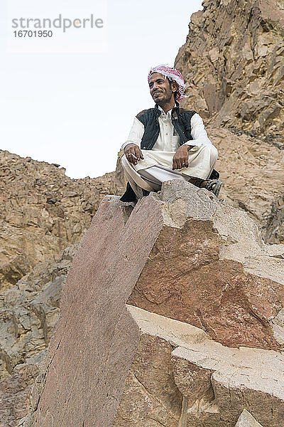 Ein Beduine sitzt auf einem Felsen in den Bergen bei Nuweiba