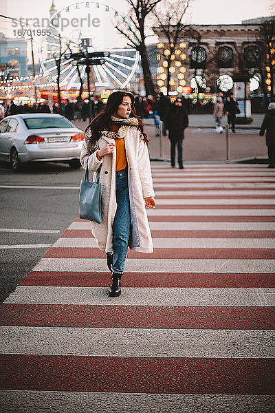 Teenager-Mädchen in warmer Kleidung beim Überqueren der Straße in der Stadt im Winter