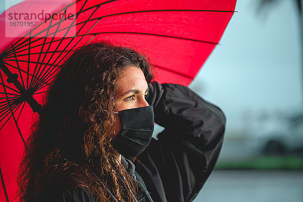 Porträt einer lockigen Frau mit einem roten Regenschirm in Palma  Spanien