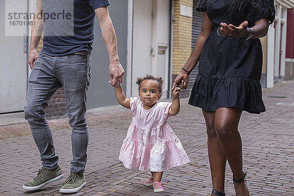 Frontalansicht einer Familie  die mit ihrer kleinen Tochter spazieren geht