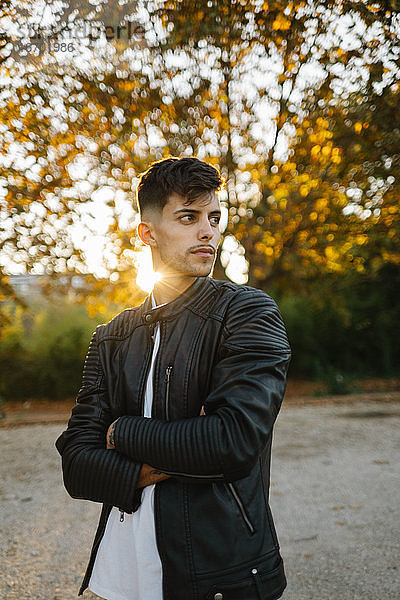 Hübscher Junge in Lederjacke posiert in einem herbstlichen Sonnenuntergang