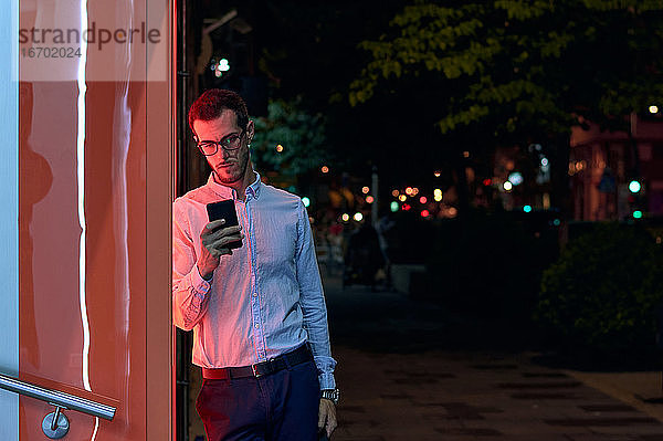Junger Geschäftsmann schaut nachts auf sein Telefon. Entrepreneur  Bus