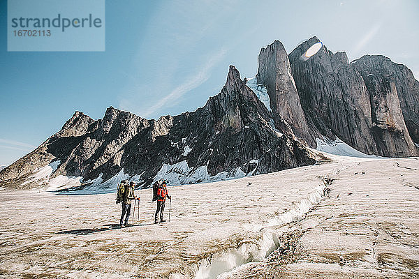 Zwei Forscher stehen auf dem Glcier unterhalb steiler Berggipfel.