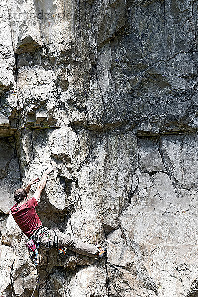 Mann klettert auf Kalksteinfelsen in Swanage / UK