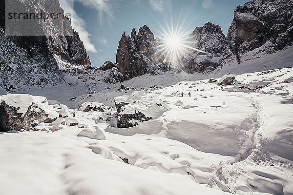 Zwei Wanderer beim Abstieg durch Felsen auf dem verschneiten Weg vor Peaks