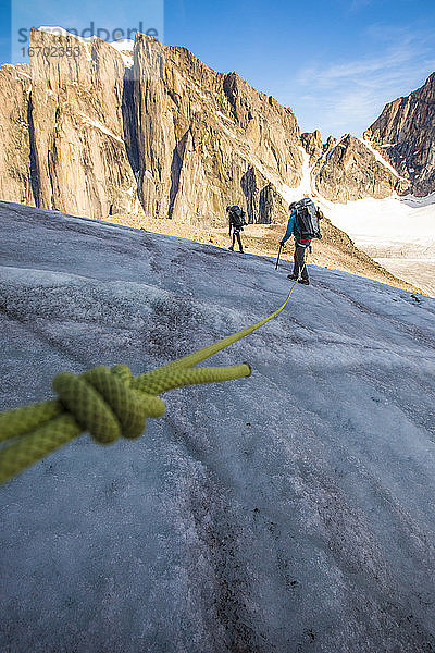 Ein Team von Bergsteigern überquert einen Gletscher im Hochgebirge.