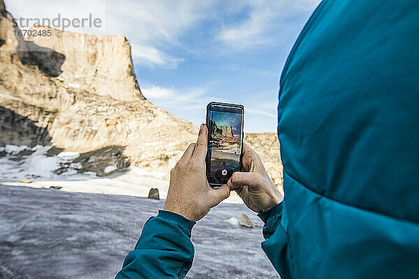 Ein Bergsteiger fotografiert den Berg Asgard mit seinem Handy.