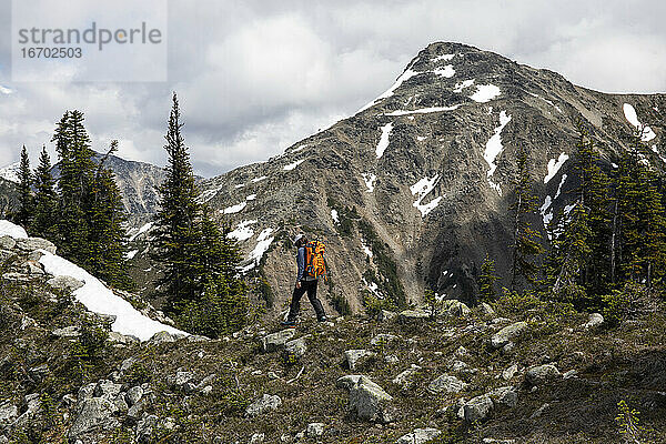 Wanderer erkundet bewaldete Berge und wandert vor einem felsigen Abhang