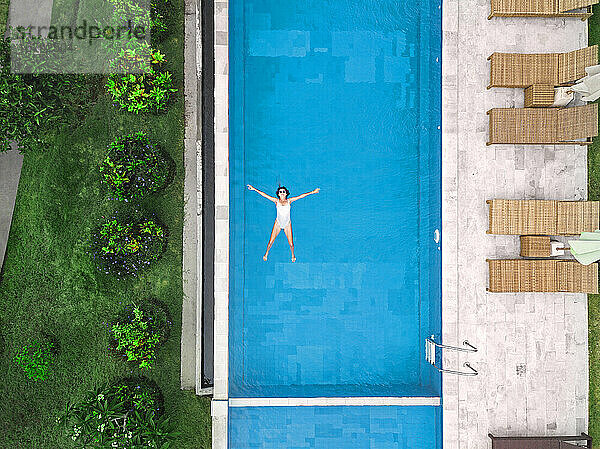 Luftaufnahme einer attraktiven Frau  die am Urlaubsort über dem Wasser schwebt