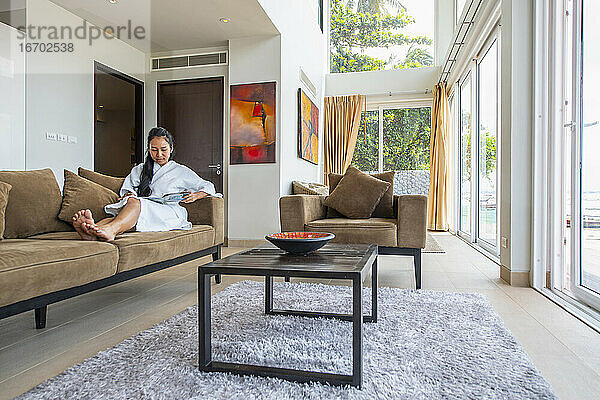schöne Frau beim Lesen im Wohnzimmer einer Luxusvilla in Phuket