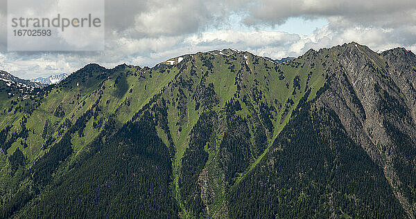 Atemberaubender Panoramablick auf das Hochland von British Columbia mit hohen felsigen Bergen  bedeckt mit grünem Wald unter bewölktem Himmel