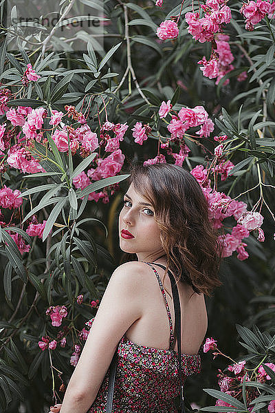 Porträt einer jungen Frau  die in der Nähe einer Oleanderblüte steht