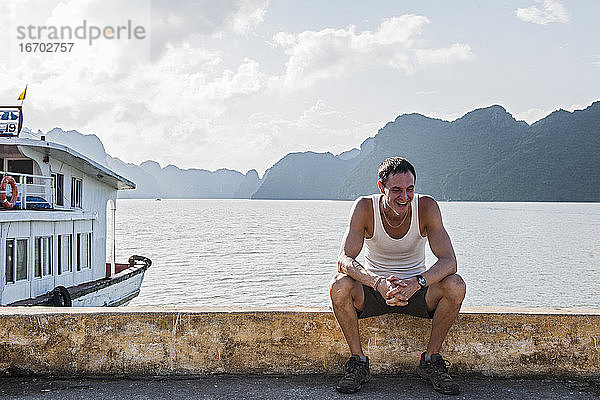 Mann sitzt am Pier in der Halong-Bucht in Vietnam