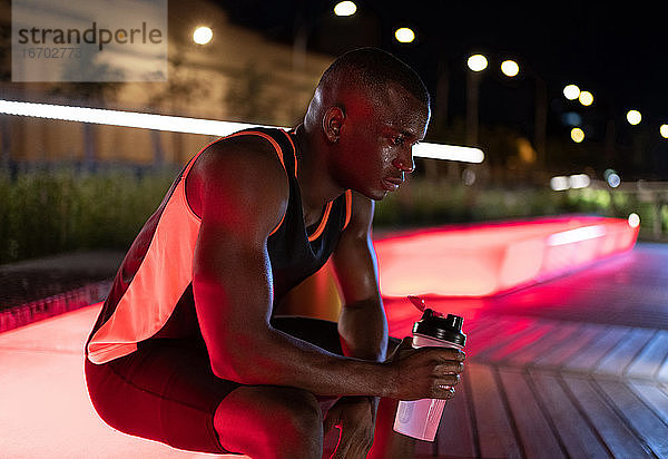 Erschöpfter afroamerikanischer Sportler trinkt Wasser