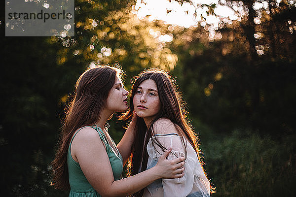 Junge Frau will ihre Freundin im Sommer im Wald küssen