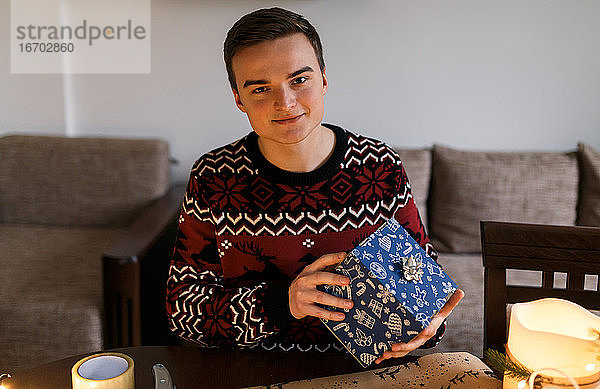 junger Mann mit einem sorgfältig verpackten Weihnachtsgeschenk